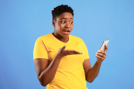 Discontented Black Lady Holding Smartphone Having Problem Over Blue Background