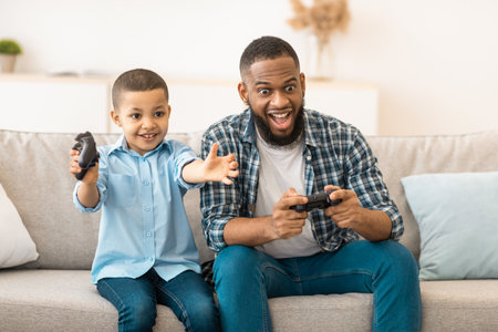 African Father And Son Having Fun Playing Video Game Indoor