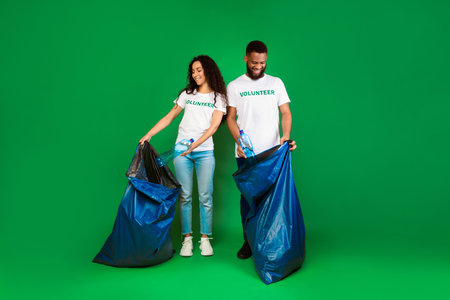Two Volunteers With Garbage Bags Picking Plastic Litter, Green Backgroundの写真素材
