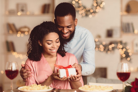 Young black man giving present box to his happy girlfriendの写真素材