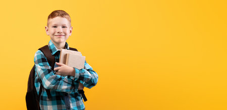 Cheerful schoolboy with backpack holding heap of books