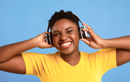 Black Woman Wearing Headphones Listening To Music Over Blue Background