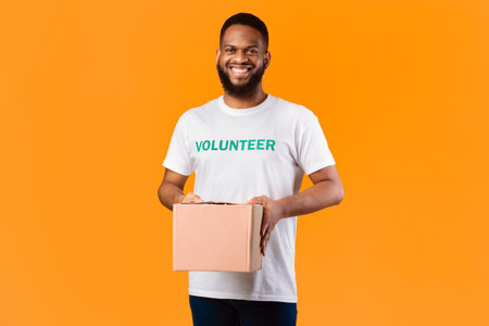 African Volunteer Man Holding Aid Box Standing On Yellow Background