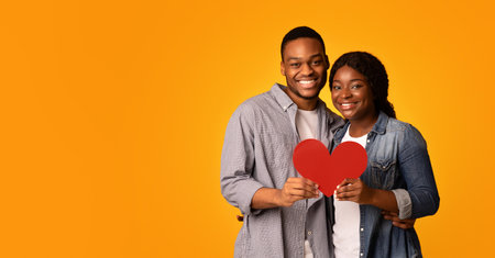 Joyful Loving Black Couple Holding Red Paper Heart Together And Huggingの写真素材