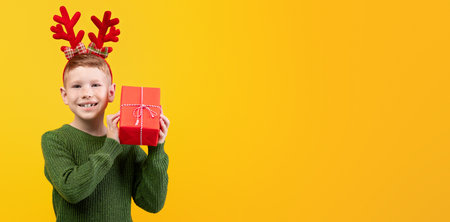 Happy kid with New Year gift over yellow backgroundの写真素材