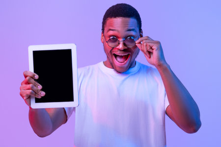 Check This App. Surprised African Guy Holding Digital Tablet With Black Screen