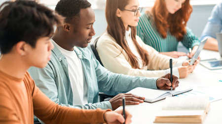 Diverse Students Sitting At Desk In Line Taking Notesの写真素材