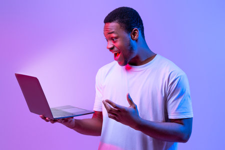 Online Offer. Surprised African Man Holding Laptop Looking At Glowing Screen