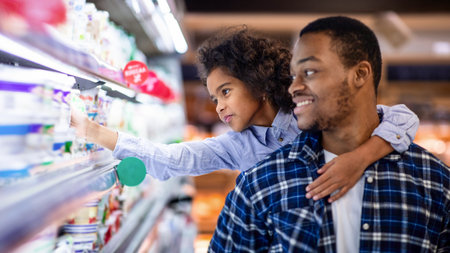 Happy black father with his cute daughter shopping for dairy products at big mallの写真素材