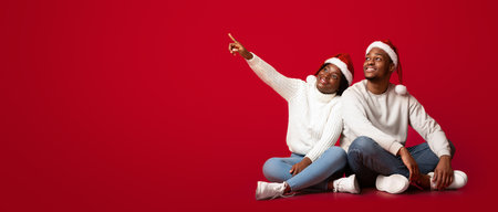 Holiday Offer. Interested Black Couple In Santa Hats Pointing At Copy Space