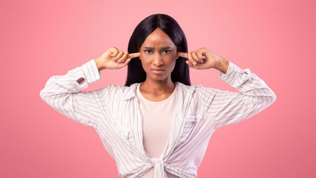 Upset black lady closing her ears with fingers, protecting from loud noise on pink studio background