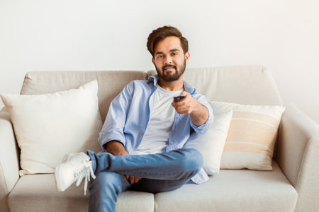 Smiling Young Middle Eastern Guy Watching TV At Home.