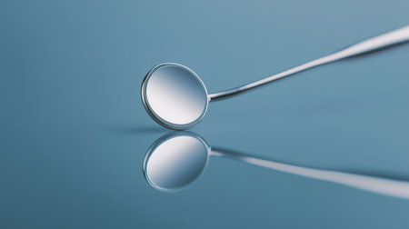 A dental mirror rests on a smooth blue surface, emphasizing its role in examining teeth and gumsの素材