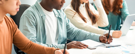 Diverse Students Sitting At Desk In Line Taking Notesの写真素材