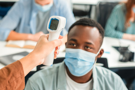 Woman with contactless thermometer measuring temperature of student, selective focusの写真素材
