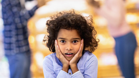 Little black girl feeling shocked while her parents arguing at big shopping mallの写真素材