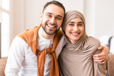 Happy Muslim Couple Embracing Sitting Together On Couch At Homeの写真素材