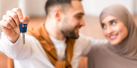 Happy muslim couple showing new house key sitting indoorsの写真素材