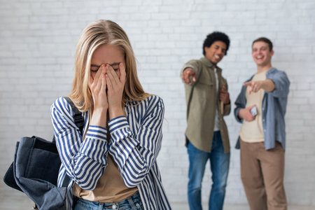 European and african american teens zoomers guys laugh at crying female with backpack in school or collegeの写真素材