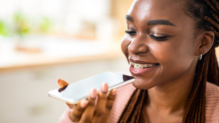 Smiling Young Black Female Using Virtual Voice Assistant Option On Smartphoneの写真素材