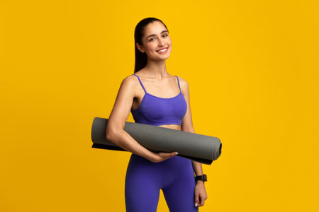 Smiling Sporty Woman Holding Yoga Mat Isolated On Orange Backgroundの写真素材