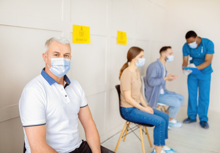 Coronavirus vaccination. Senior male patient waiting for covid-19 vaccine in queue at clinic, space for textの写真素材