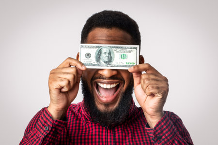 Happy Black Man Holding One Hundred Dollar Banknote, White Backgroundの写真素材