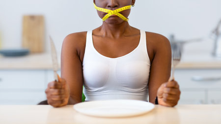 Lady Having Tied Mouth With Measuring Tape Sitting In Kitchenの写真素材