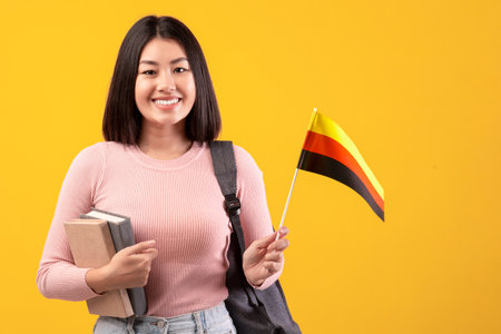 Teen happy asian woman with backpack holds notebooks and small flag of Germanyの写真素材