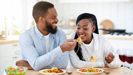 Beautiful african american couple having romantic lunch together in kitchenの写真素材