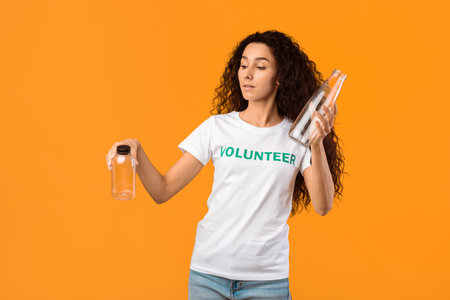 Volunteer Lady Choosing Glass Bottle Instead Of Plastic, Yellow Backgroundの写真素材