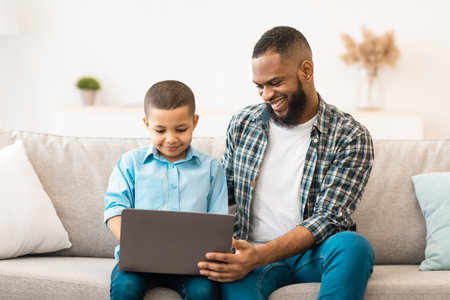 African American Boy And His Father Using Laptop At Home