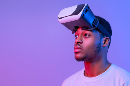 Handsome Black Man Wearing VR Glasses Looking Aside Over Purple Background
