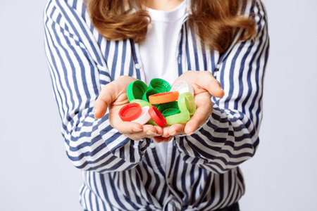 Woman holds colorful plastic bottle caps while promoting recycling efforts