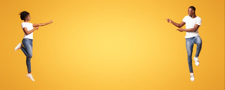 Black man and woman pointing at empty space between themの写真素材