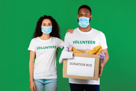 Volunteers In Protective Mask Holding Donation Box Over Green Background