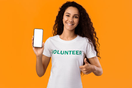 Happy Volunteer Lady Showing Smartphone Screen Gesturing Thumbs-Up, Yellow Background