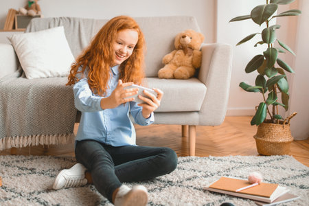Girl playing games on smart phone resting on floorの写真素材