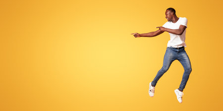 Millennial african american man pointing at copy space while jumpingの写真素材