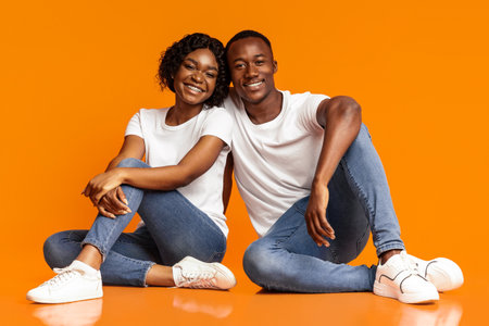 Carefree african american lovers sitting on floor, studio shotの写真素材