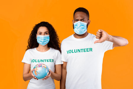 Volunteers Wearing Face Masks Holding Earth Globe Gesturing Thumbs-Down, Studio