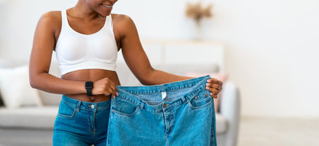 Black Lady Holding Jeans Too Big After Weight-Loss At Home