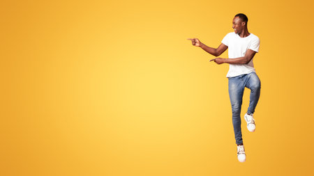 Excited black guy jumping up and showing copy spaceの写真素材