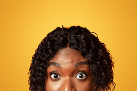 Closeup of black woman surprised eyes, orange background
