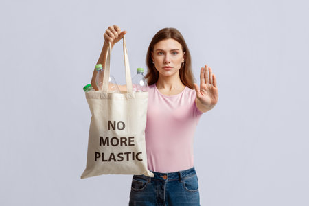 Woman holding eco bag with no more plastic inscription, showing stop gesture