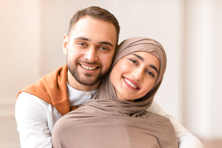 Cheerful Young Muslim Couple Hugging Posing Standing Indoors At Homeの写真素材