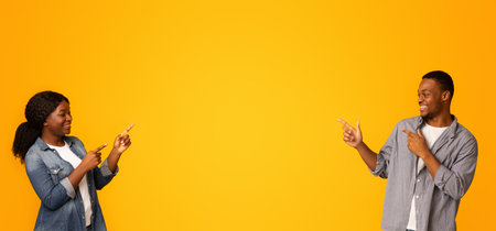 Look There. Joyful black couple pointing at copy space between themの写真素材