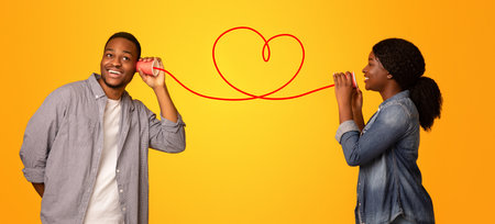 Love Message. Black woman whispering romantic words to boyfriend via tin phone