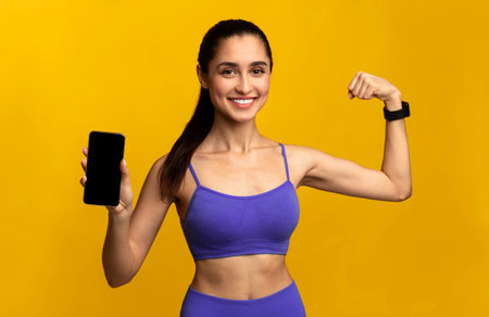 Happy sporty woman showing phone with blank screenの写真素材