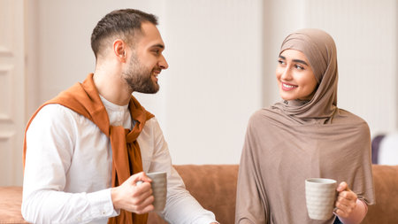 Young Muslim Couple Talking And Flirting Drinking Coffee At Homeの写真素材